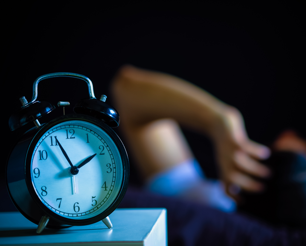 Someone Sleeping With Alarm Clock On Side Table