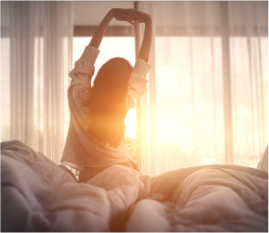 Woman stretching while looking at the sunrise outside