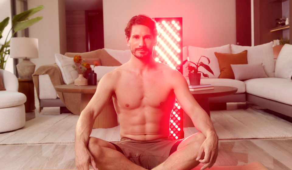 Man sitting in front of a Red Light Device cross-legged on living room floor